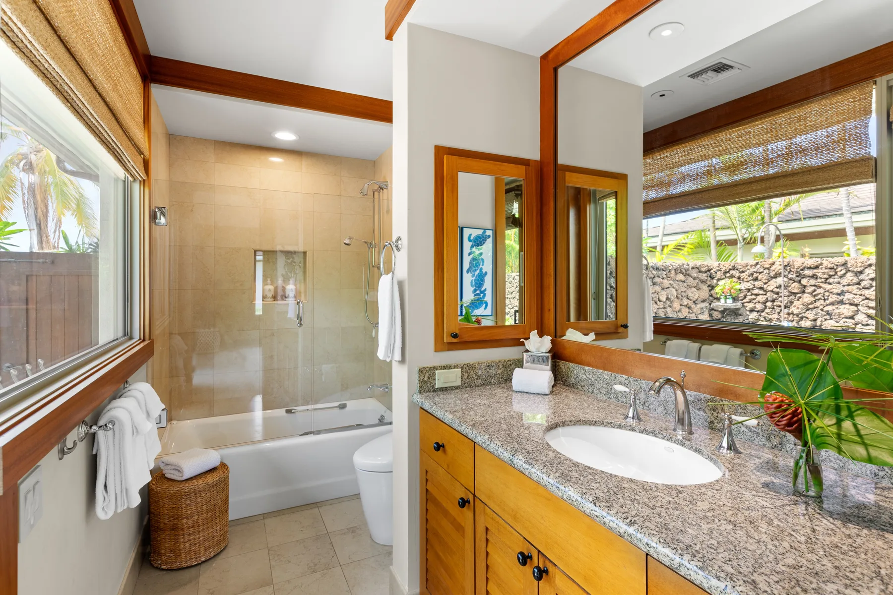 A bathroom with a bathtub, glass shower screen, and a wide vanity.