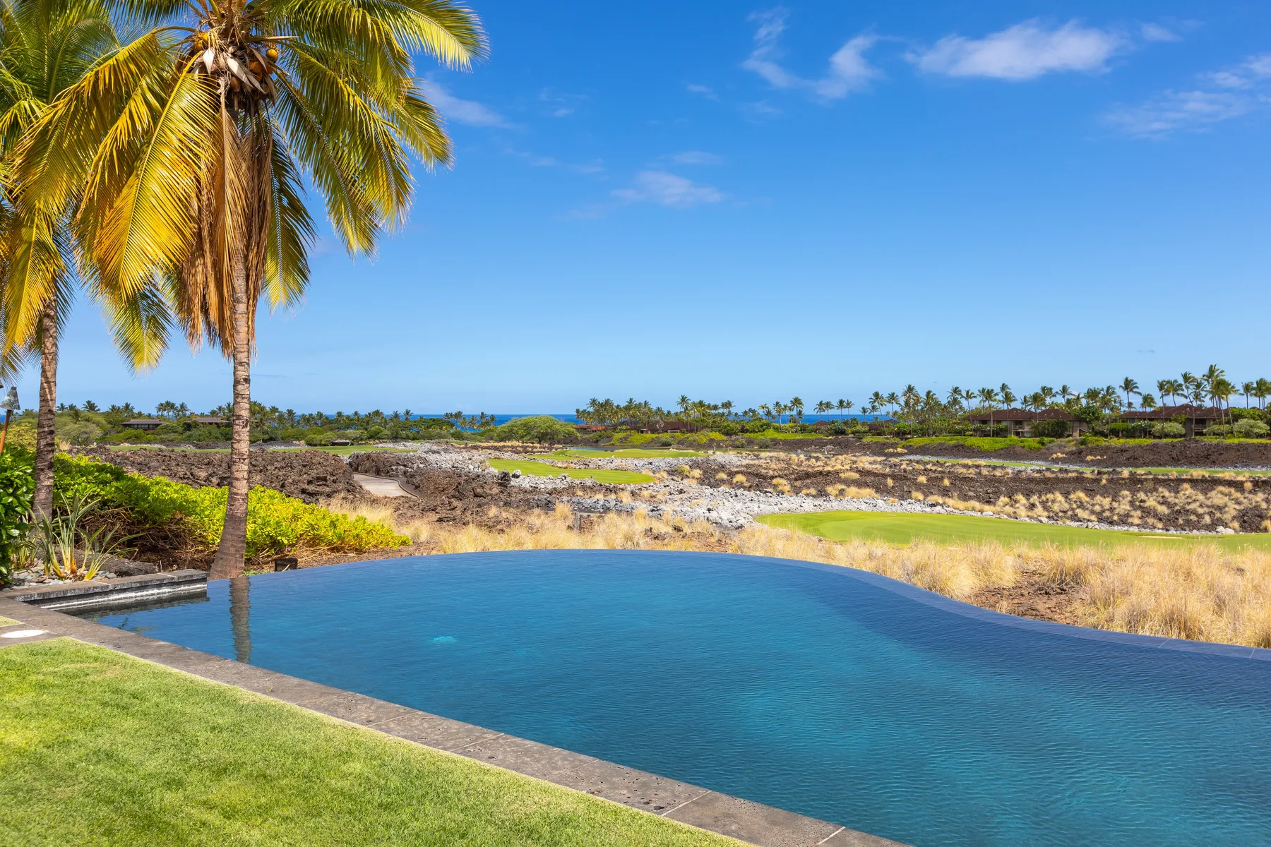 An outdoor swimming pool overlooks a dry landscape beneath a clear blue sky.