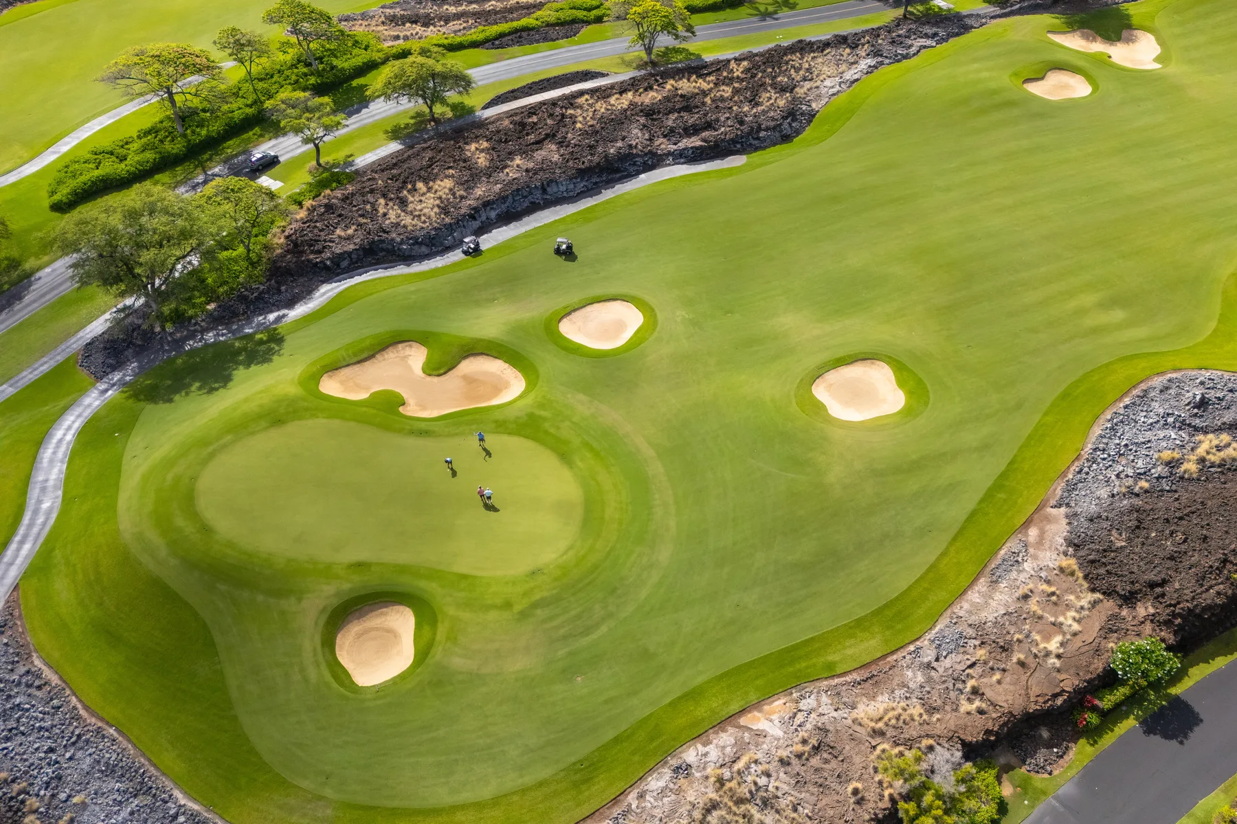 An aerial view of a golf green with sand bunkers and surrounding paths.