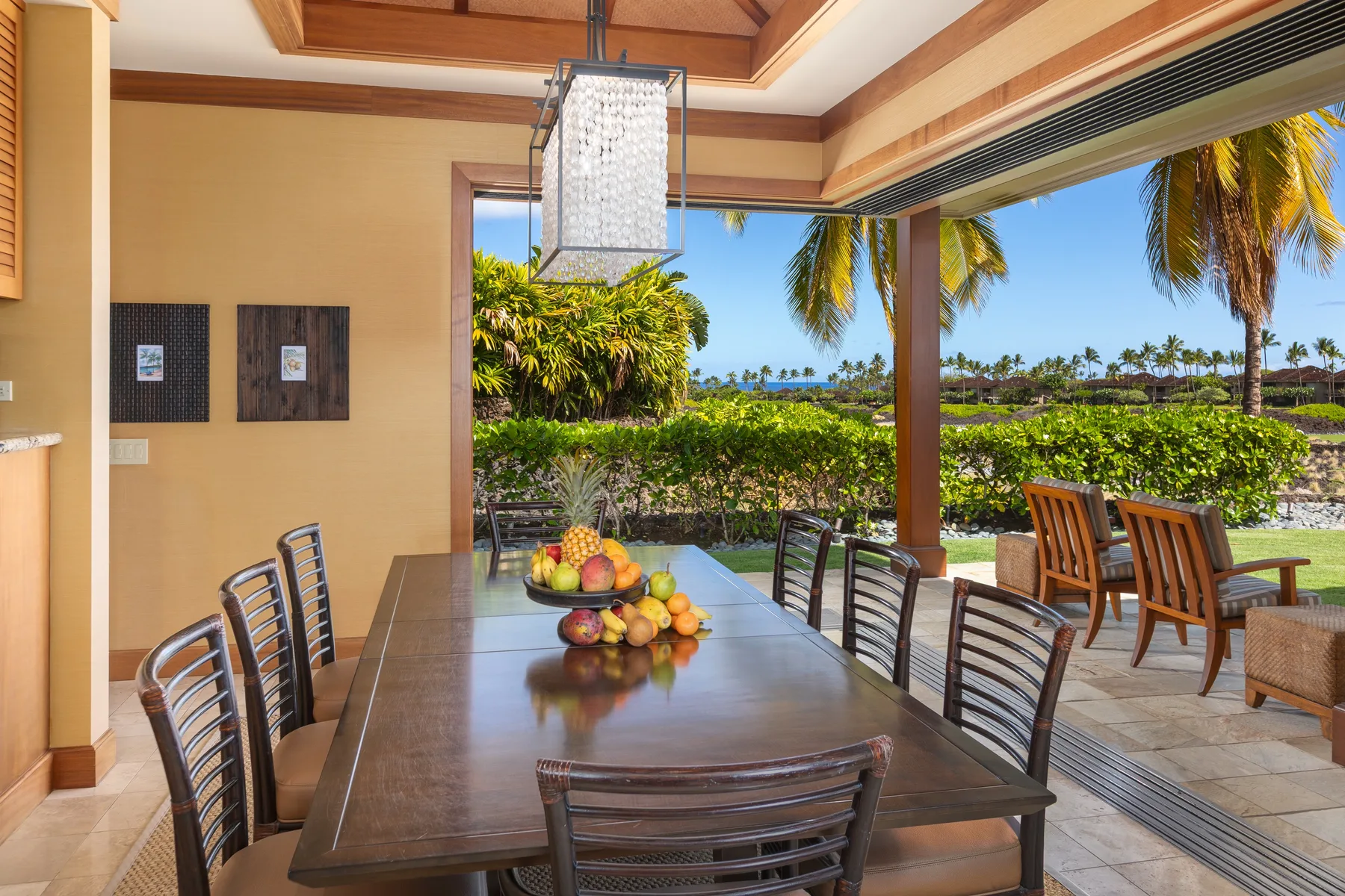 A dining area opens onto a patio with palm trees and ocean views.