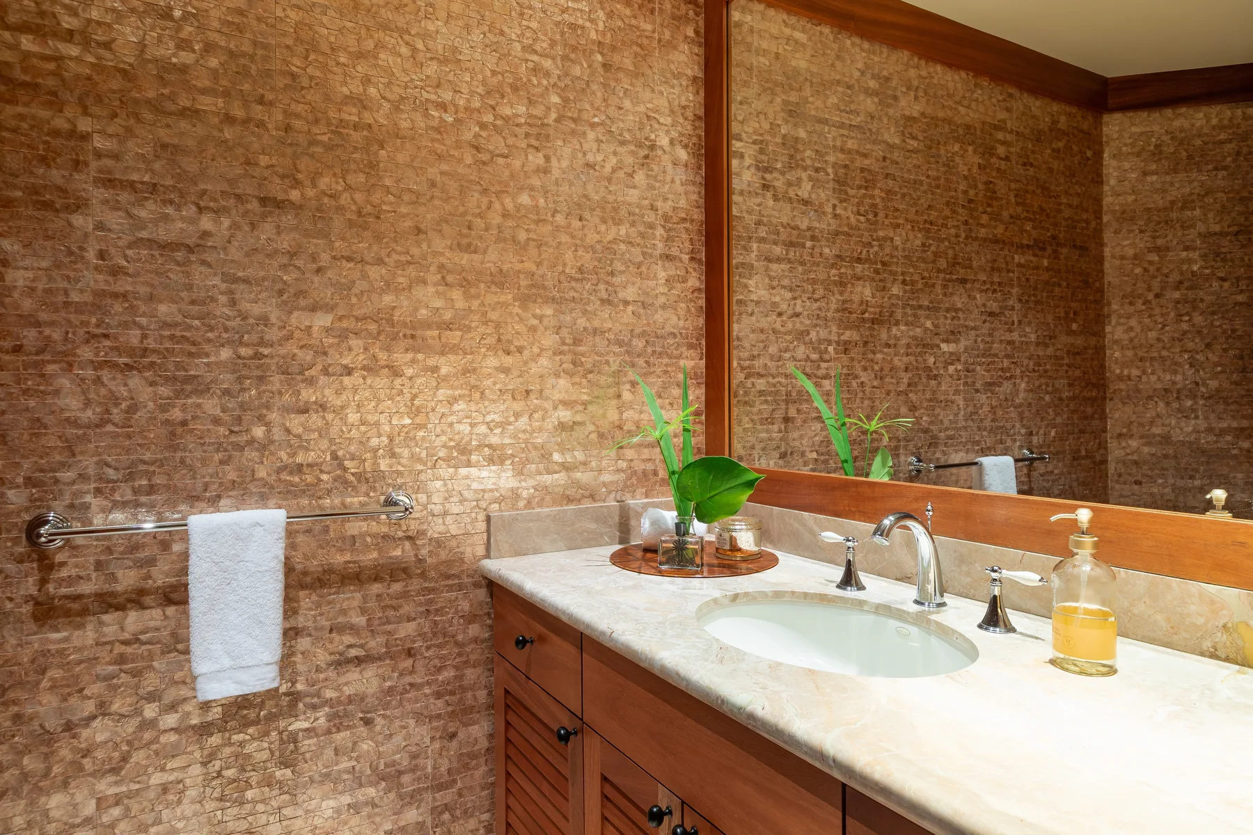 A bathroom vanity with a sink, mirror, and small potted plant.