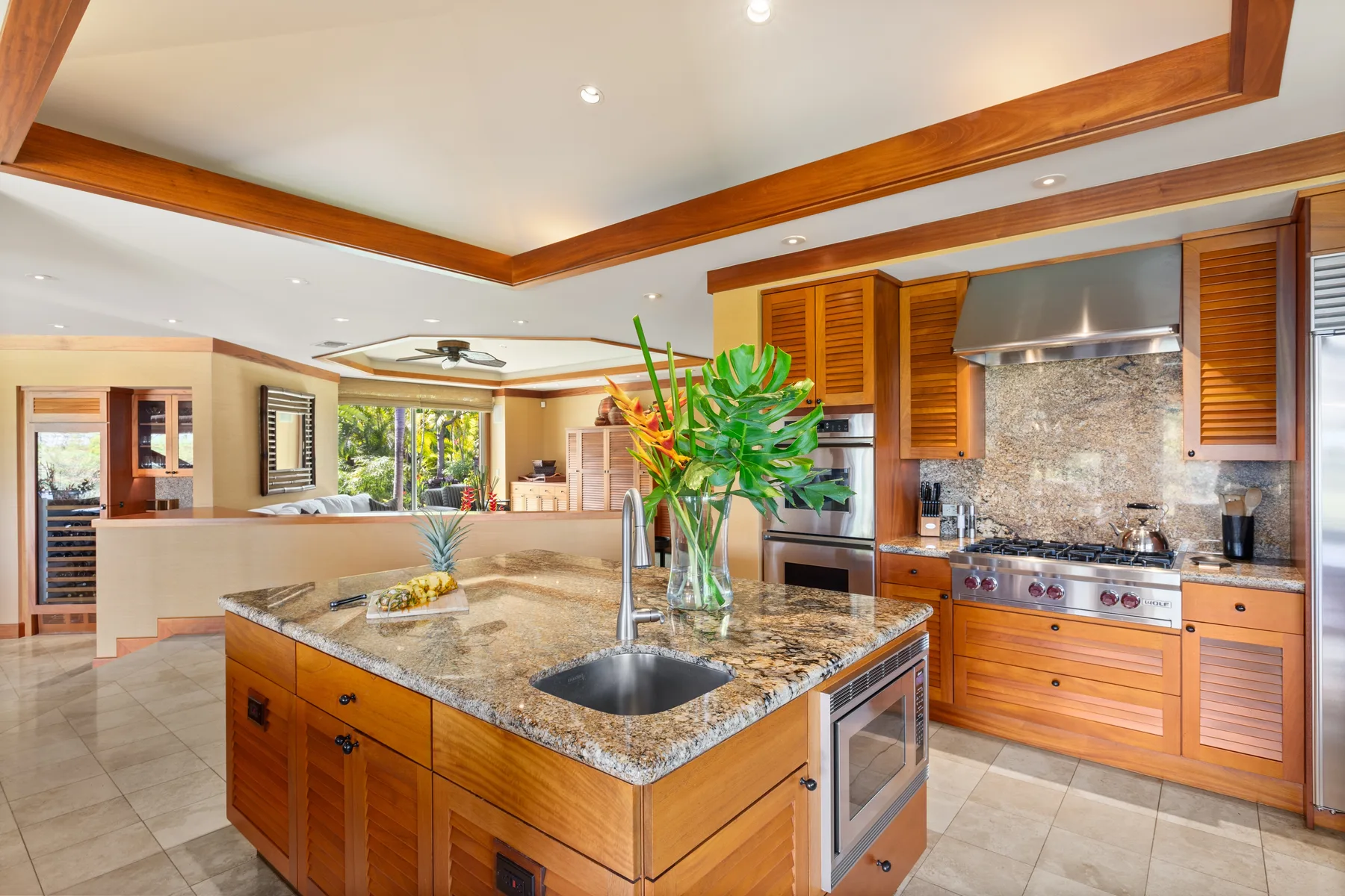 A spacious kitchen features a central island with a sink and surrounding wooden cabinetry.