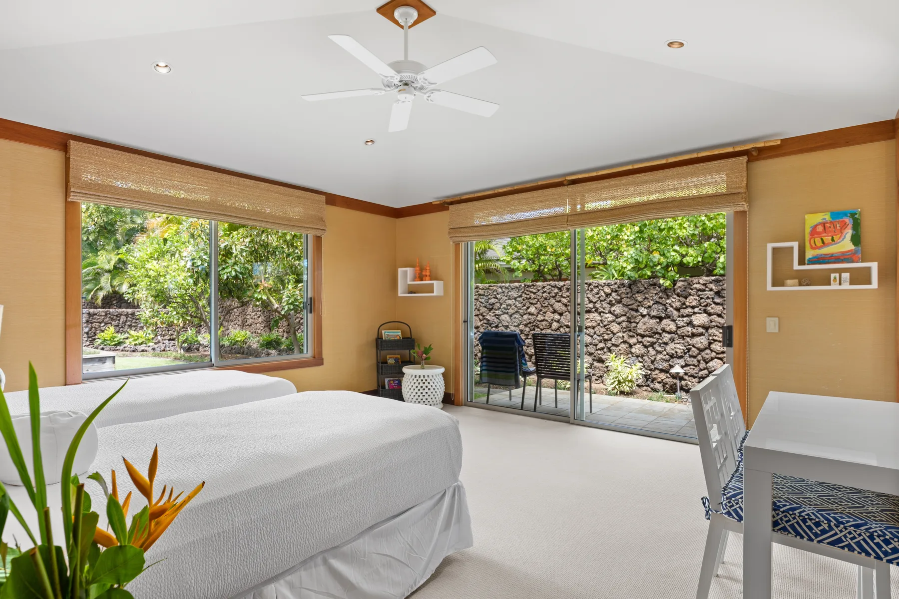 A bedroom with a bed, large windows, and sliding glass doors opening to greenery.