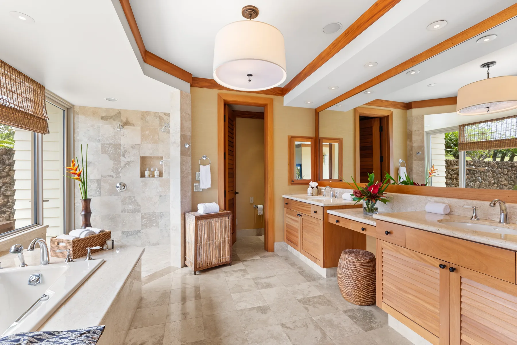 A spacious bathroom with a bathtub, stone-tiled shower area, and long vanity.
