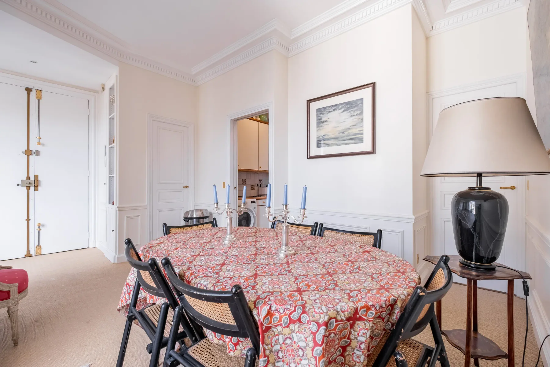 Comedor con un mantel estampado y una obra enmarcada en la pared.
