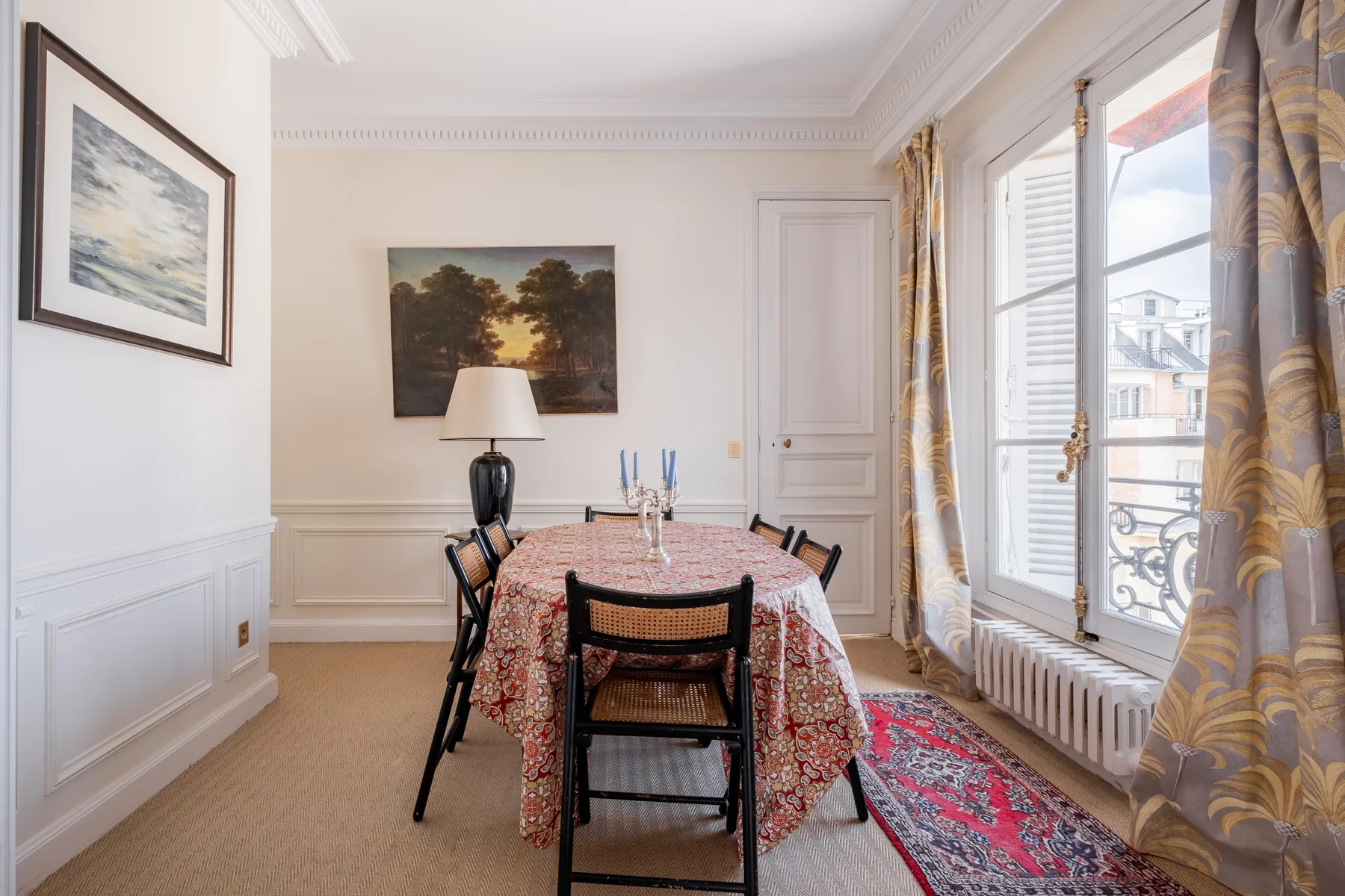 Un comedor con una mesa puesta bajo cuadros enmarcados.