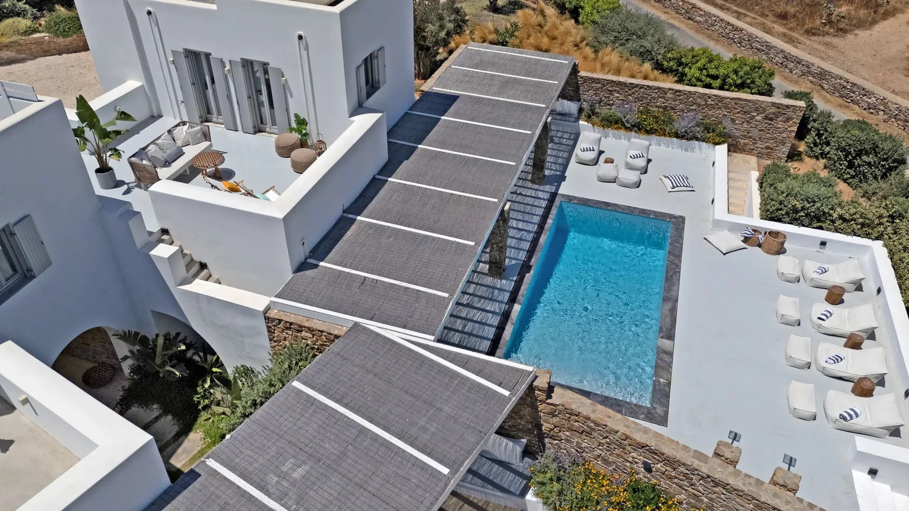 An aerial view shows a modern villa with a swimming pool and outdoor seating.
