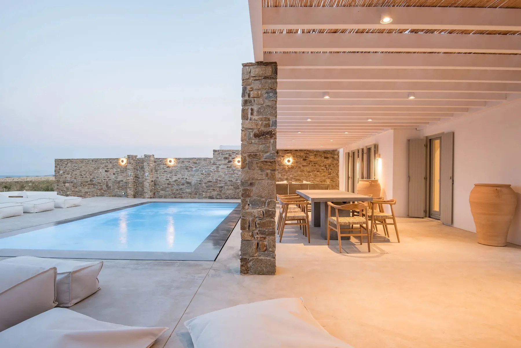 A covered outdoor dining area beside a swimming pool.
