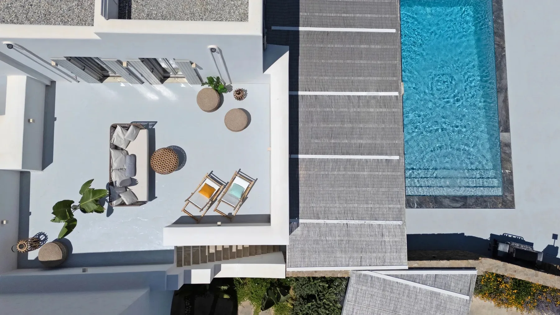 An aerial view shows a modern terrace beside a swimming pool.
