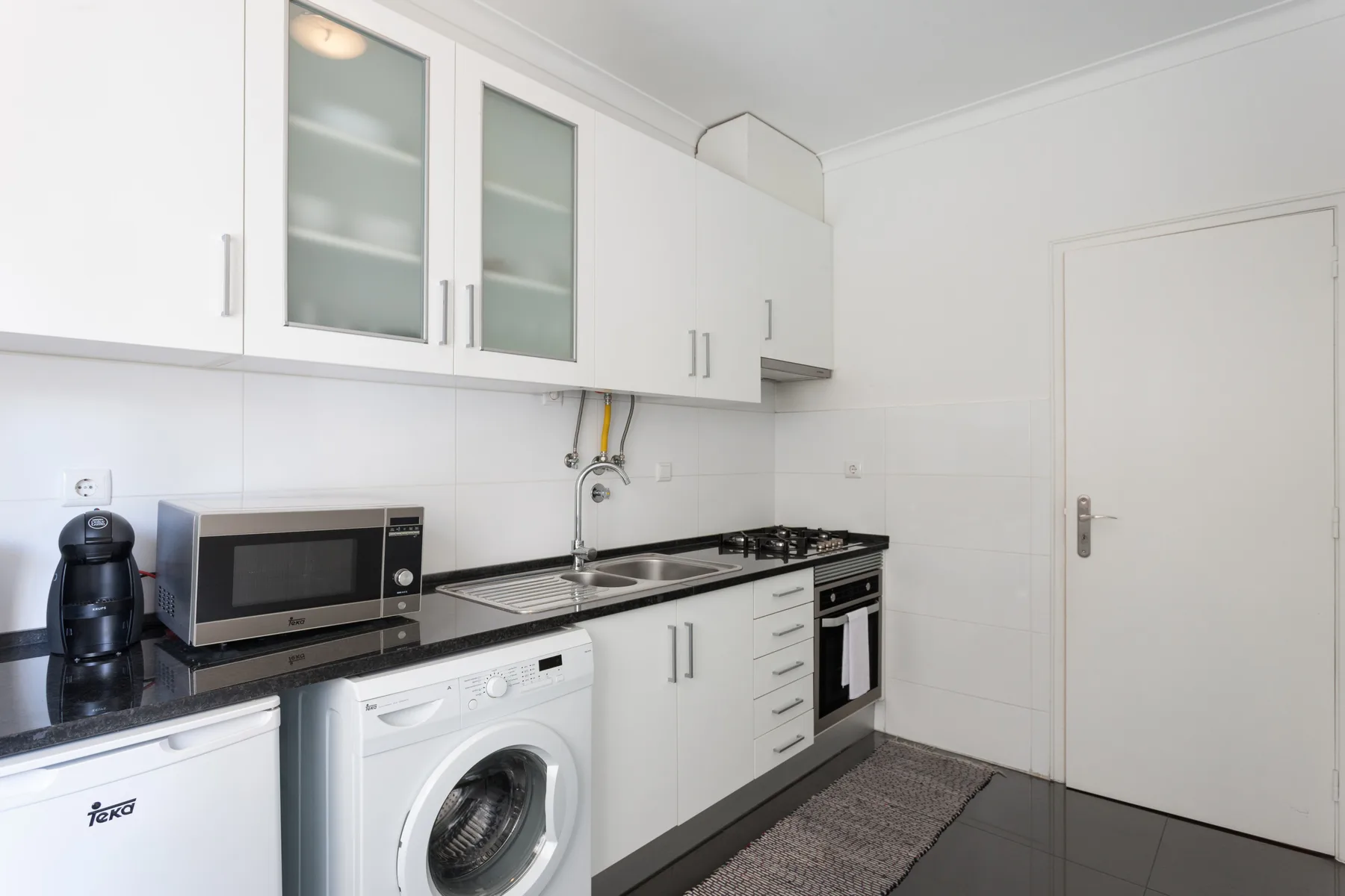 A bright kitchen with white cabinets, a countertop, and built-in appliances.