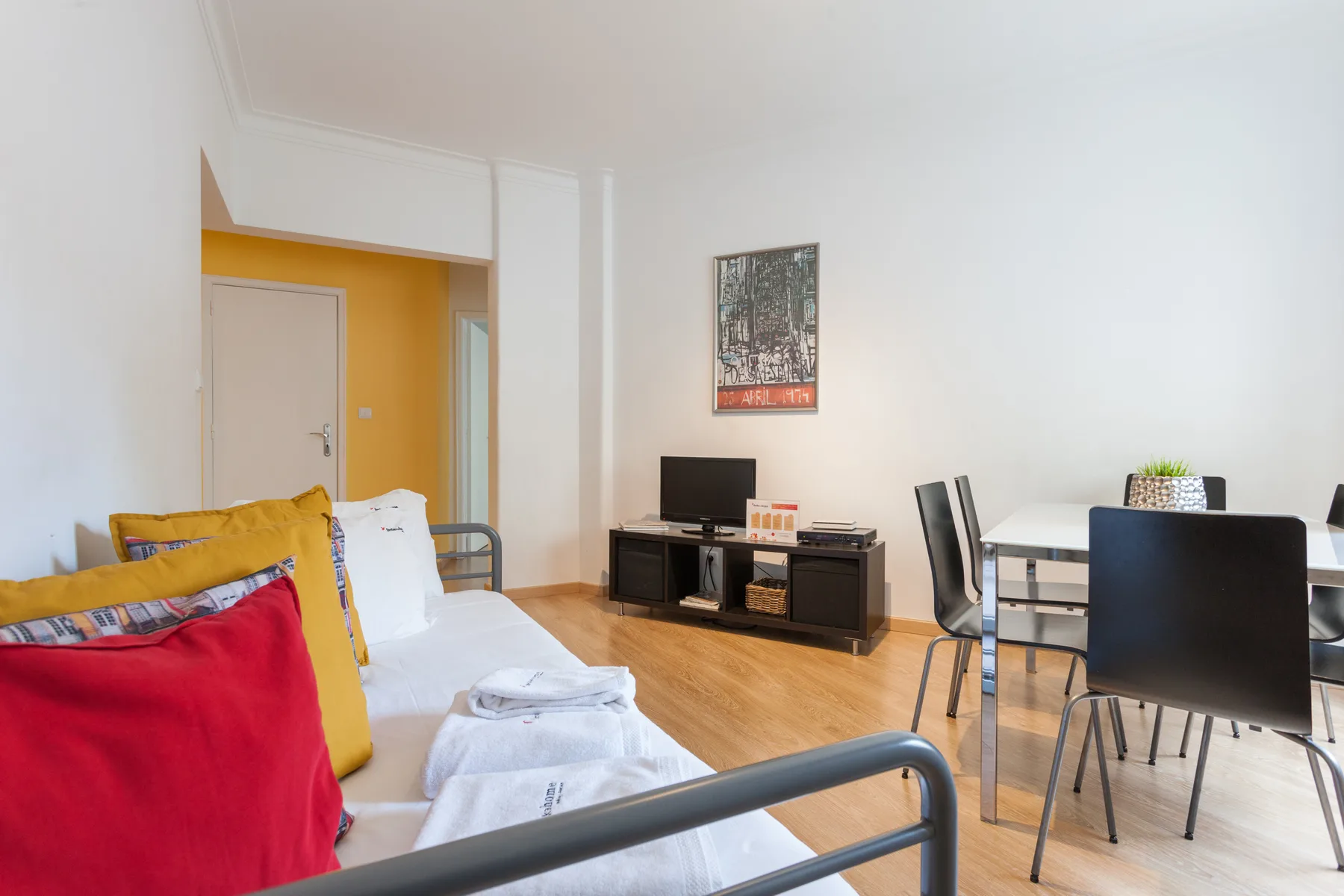 A bright room with seating, a television, and a dining table.