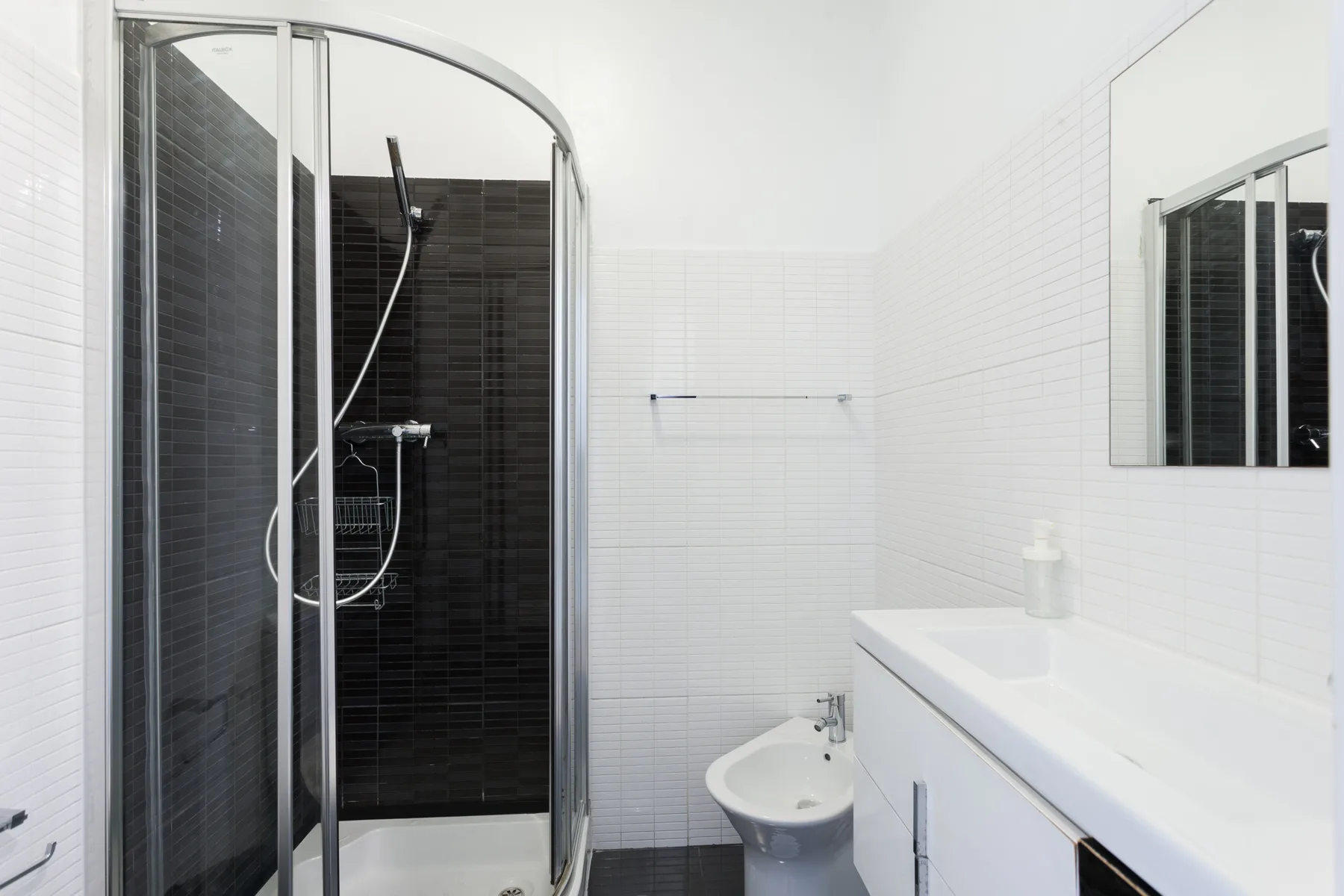 A bright bathroom with a shower, sink, and wall mirror.