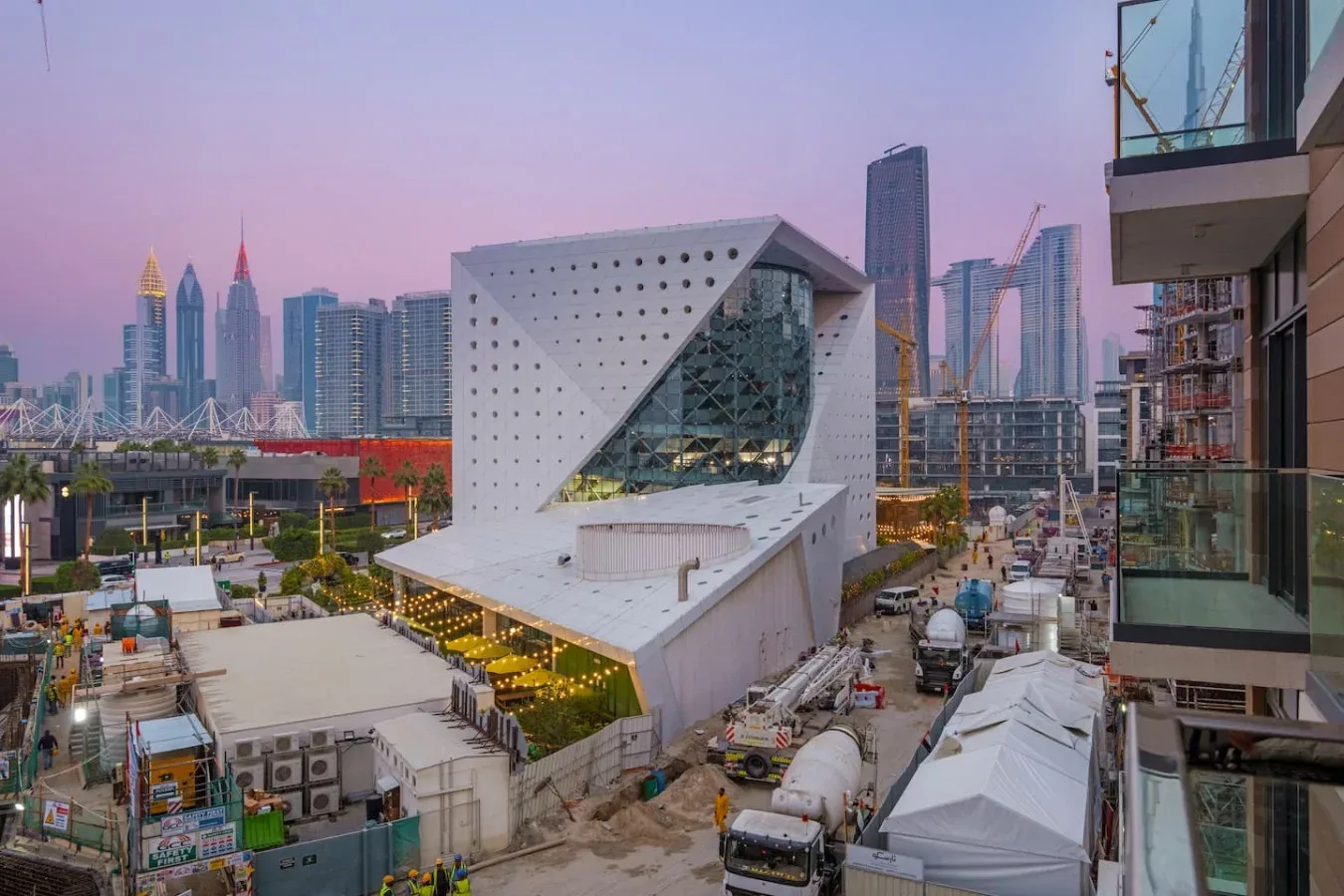 Un edificio moderno y angular se alza en una obra, con el horizonte urbano al fondo.