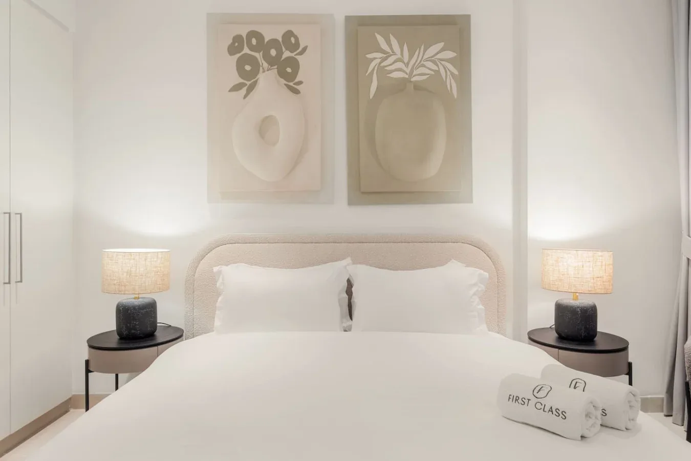 Un dormitorio luminoso con una cama grande, mesitas de noche y láminas botánicas enmarcadas.