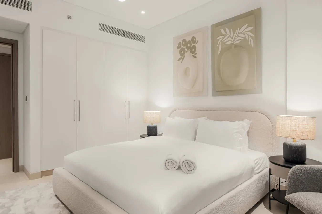 Un dormitorio luminoso con una cama grande y cuadros botánicos enmarcados.