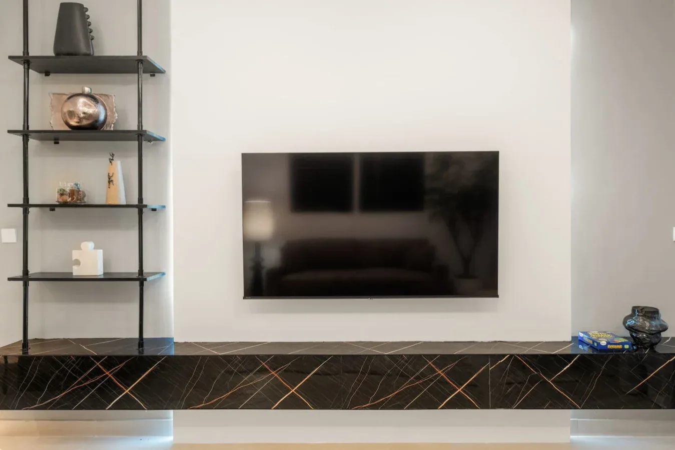Una pared de sala de estar tiene un televisor montado sobre un revestimiento oscuro de mármol.
