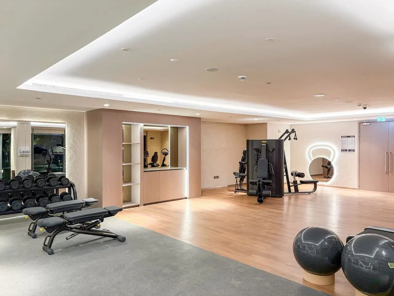 Una sala de ejercicios luminosa con equipos, bancos de pesas y espacio libre.