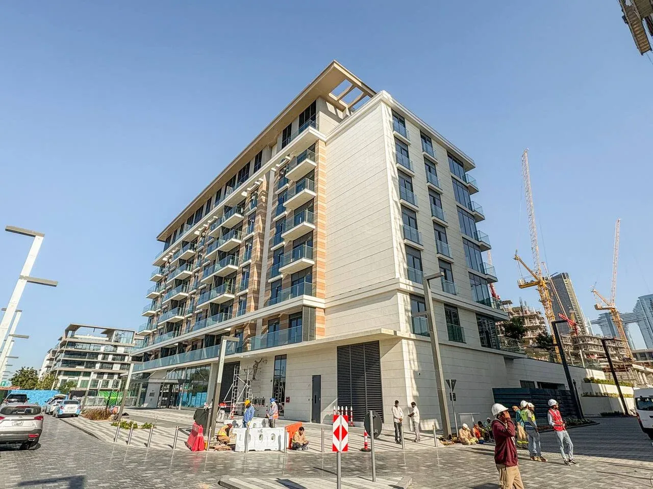 Un edificio moderno de varias plantas se alza junto a una obra en construcción.