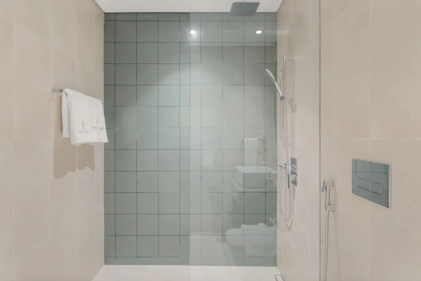 Una ducha de baño con azulejos, paneles de vidrio y una toalla colgada cerca.