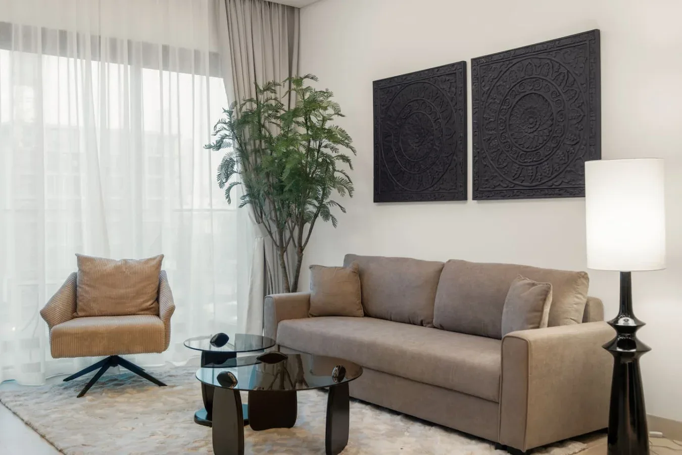 Una sala de estar con un sofá, un sillón y una mesa de centro de vidrio.