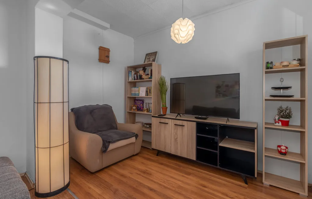 A living room with a recliner beside a television and shelving.