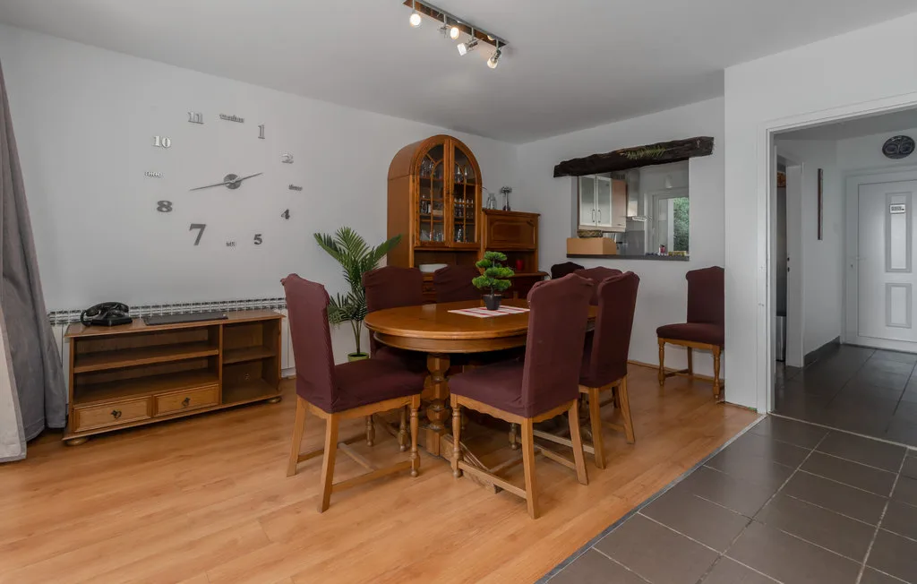 A dining area with a wooden table and upholstered seating beside an open kitchen.