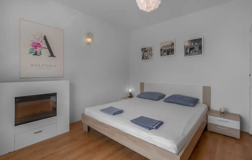 A bedroom with a double bed, bedside tables, and framed wall art.