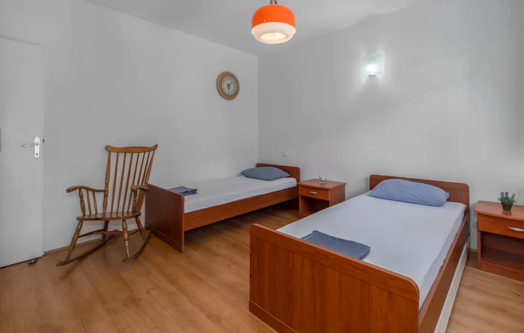 A bedroom with two single beds and a wooden rocking chair.