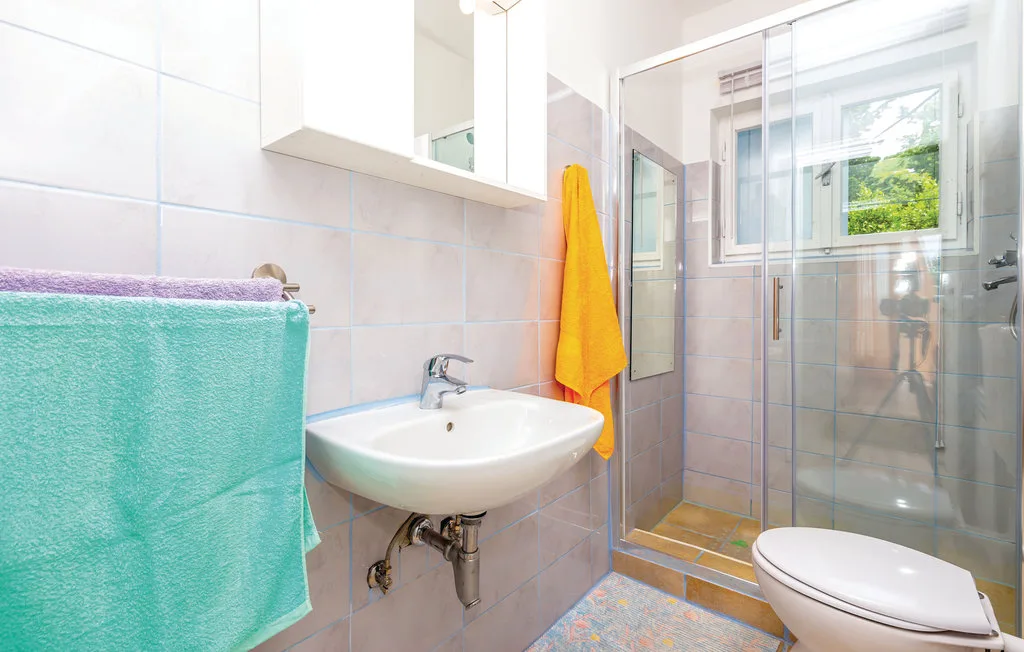 A tiled bathroom with a sink, shower, and toilet.