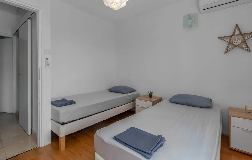 A bright bedroom with two beds and simple white bedding.