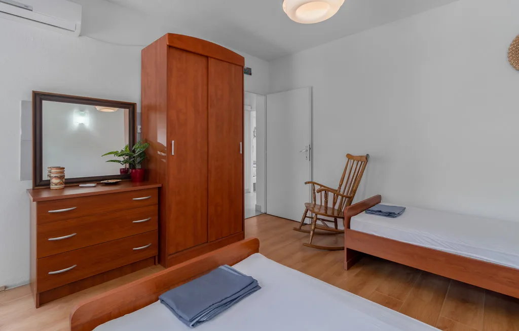 A bedroom with beds, wooden storage furniture, and a rocking chair.