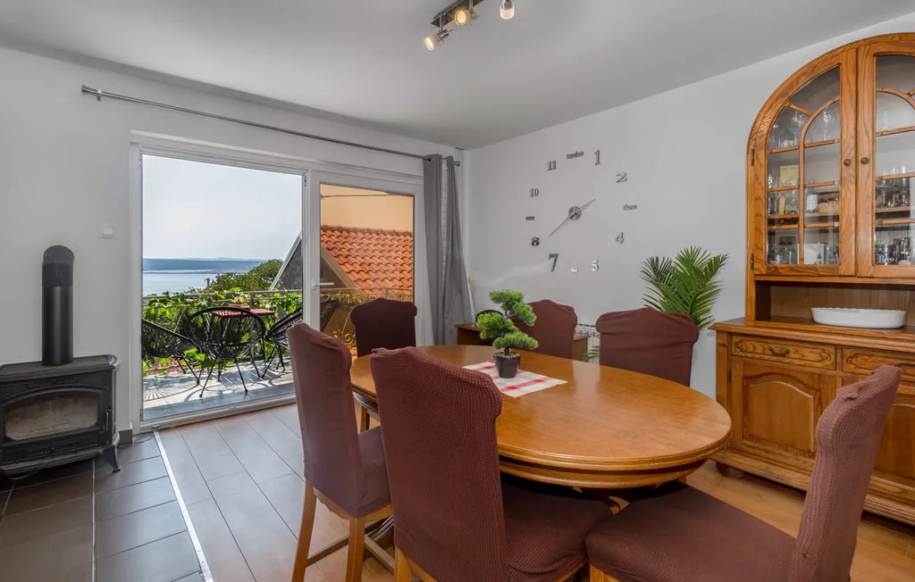 Un comedor con mesa de madera y asientos junto a puertas corredizas de vidrio.