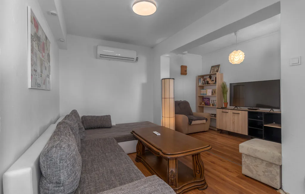 A living room with gray seating, a wooden coffee table, and a television.