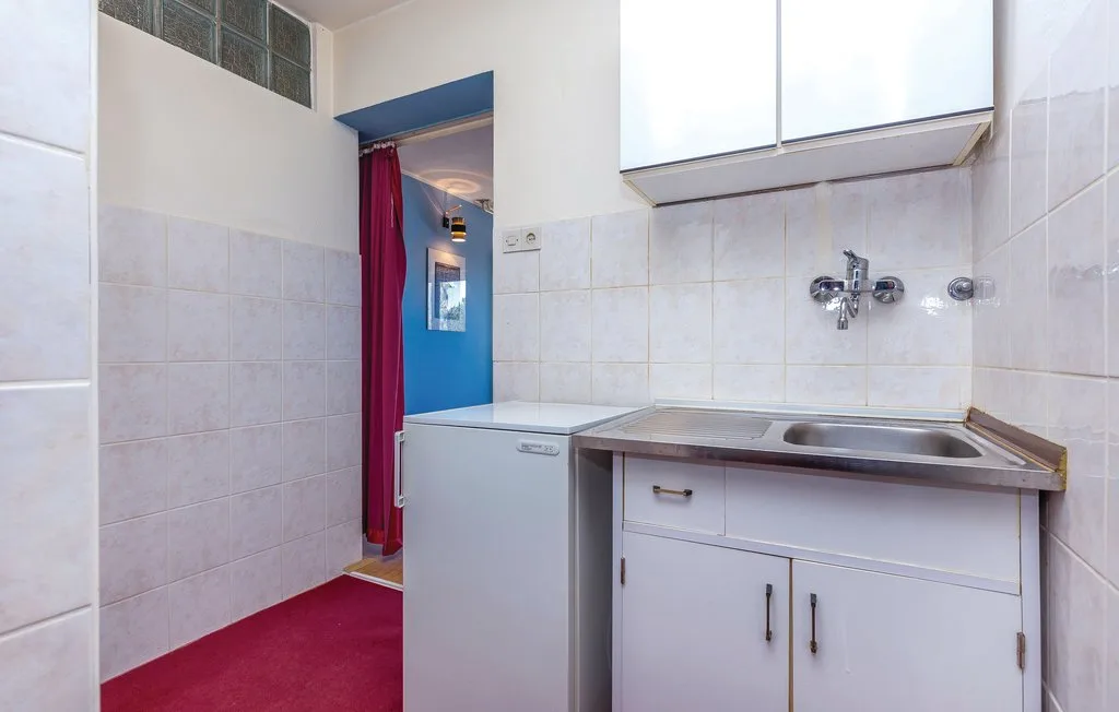 A tiled utility room with a sink, cabinets, and a washing machine.