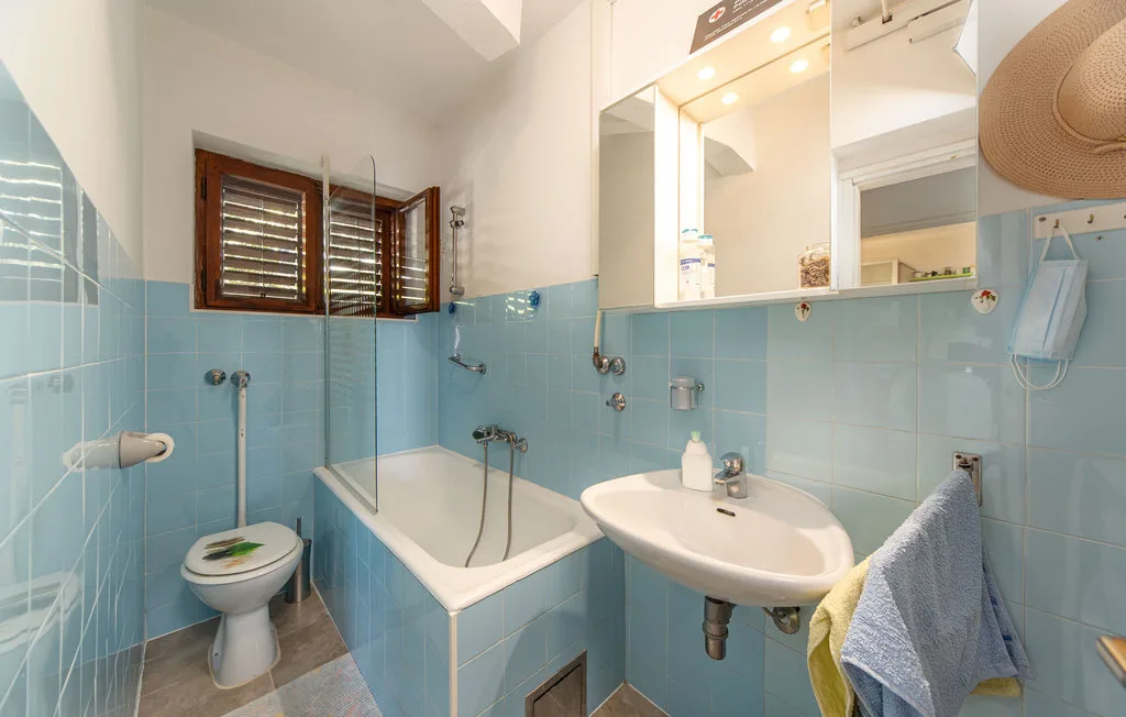 A bathroom with a bathtub, sink, and light blue tiled walls.