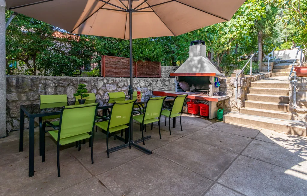 Un comedor al aire libre con asientos verdes y una parrilla integrada.