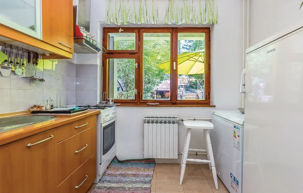 A bright kitchen with wooden cabinets, a window, and a small stool.