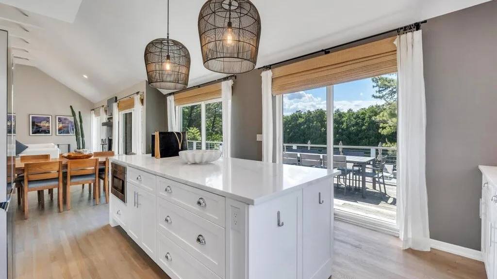 A bright open-plan dining area with a white kitchen island beside large windows.