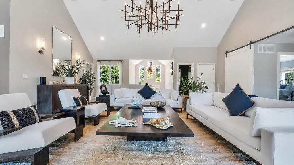A bright living room with white seating arranged around a central coffee table.