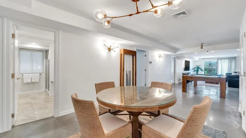 A dining area with a round table and seating, opening into a living space.