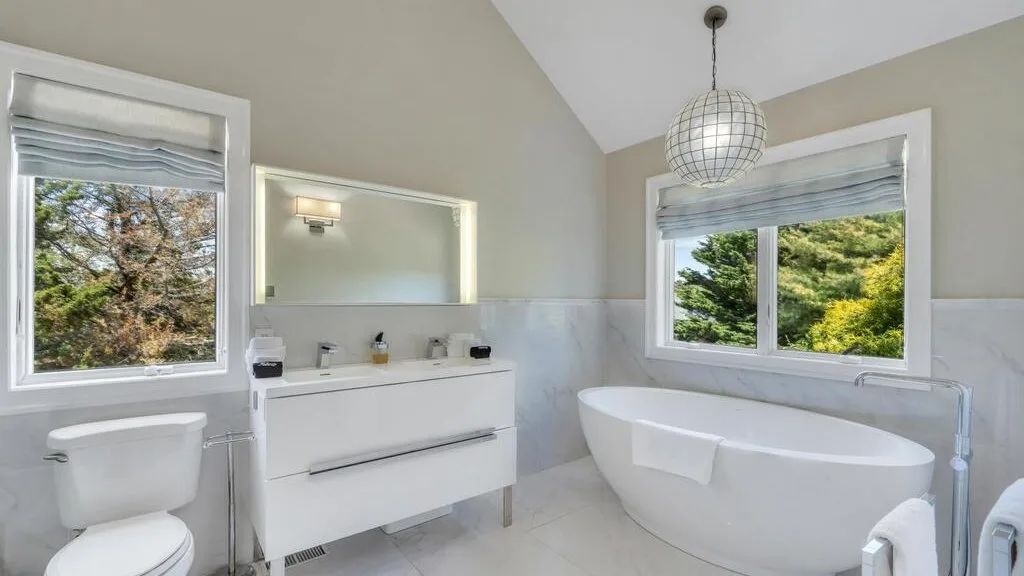 A bright bathroom with a freestanding bathtub and wall-mounted vanity.