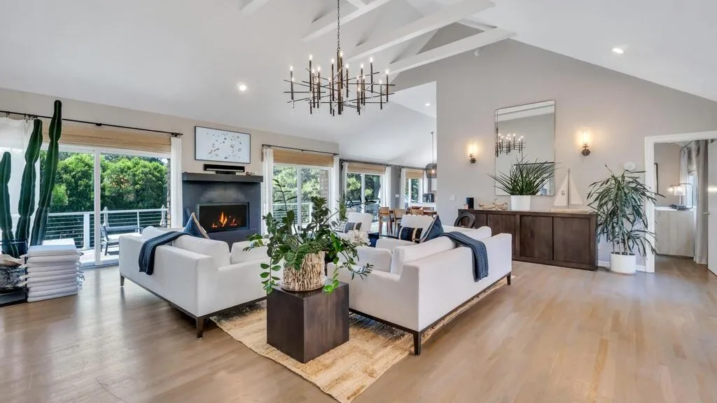 A bright living room with seating arranged around a fireplace and a low table.