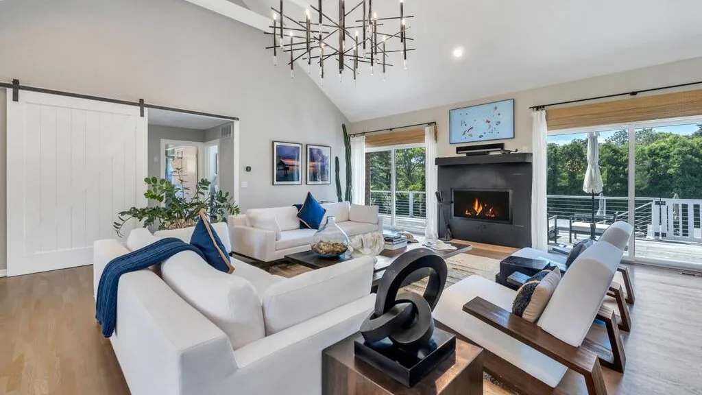 A bright living room with seating arranged around a fireplace and large windows.