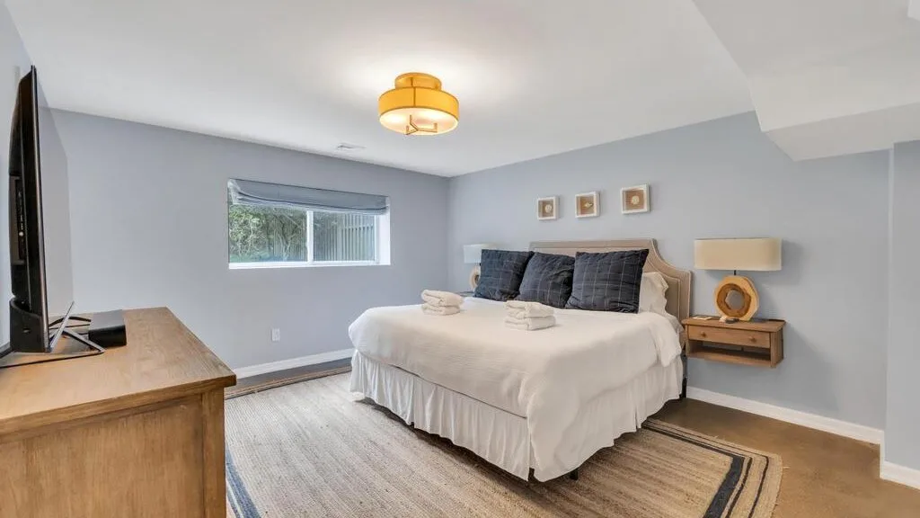 A bedroom with a neatly made bed, bedside tables, and a window.