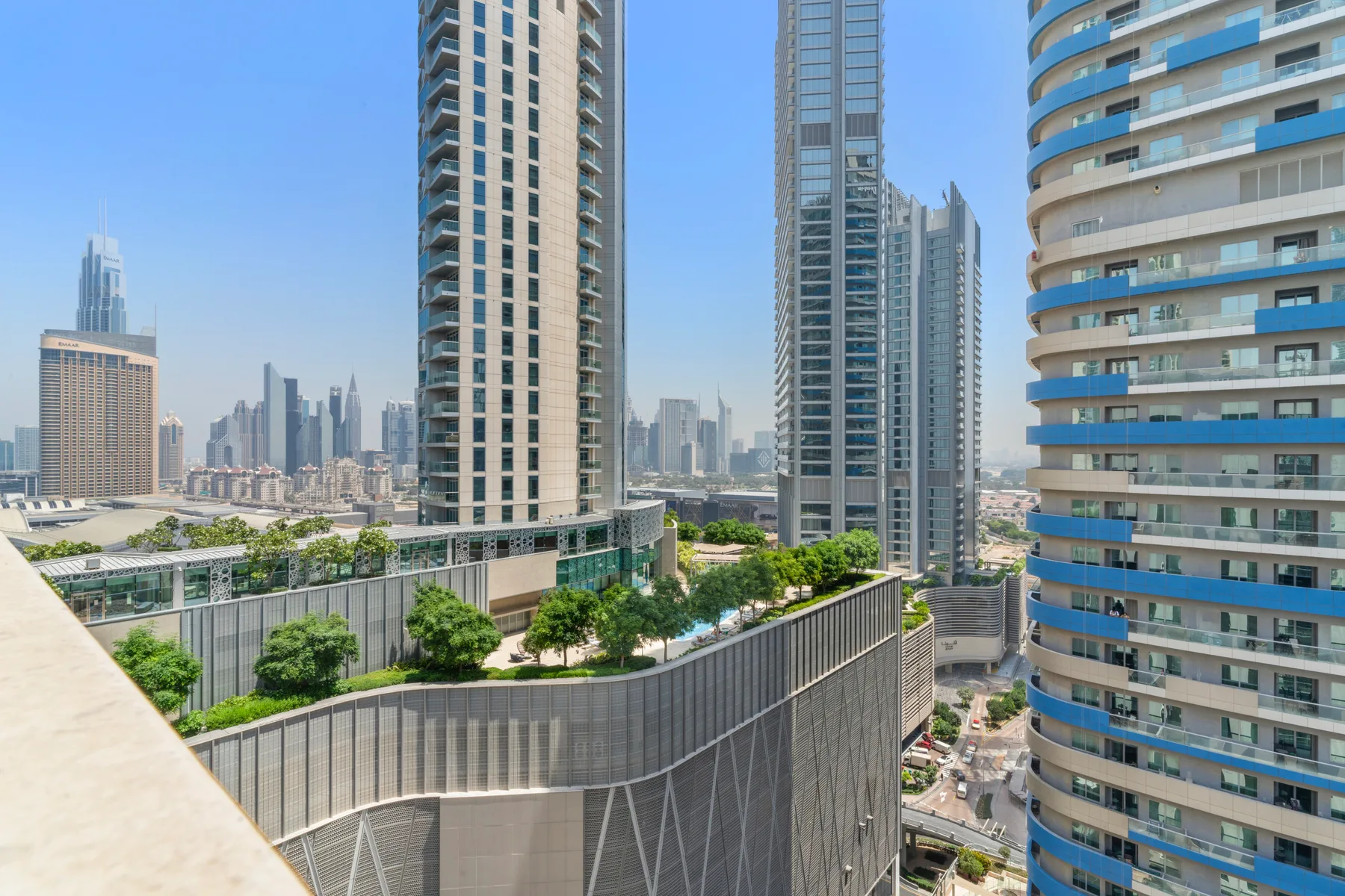 Un horizonte urbano se alza detrás de edificios modernos y terrazas ajardinadas.