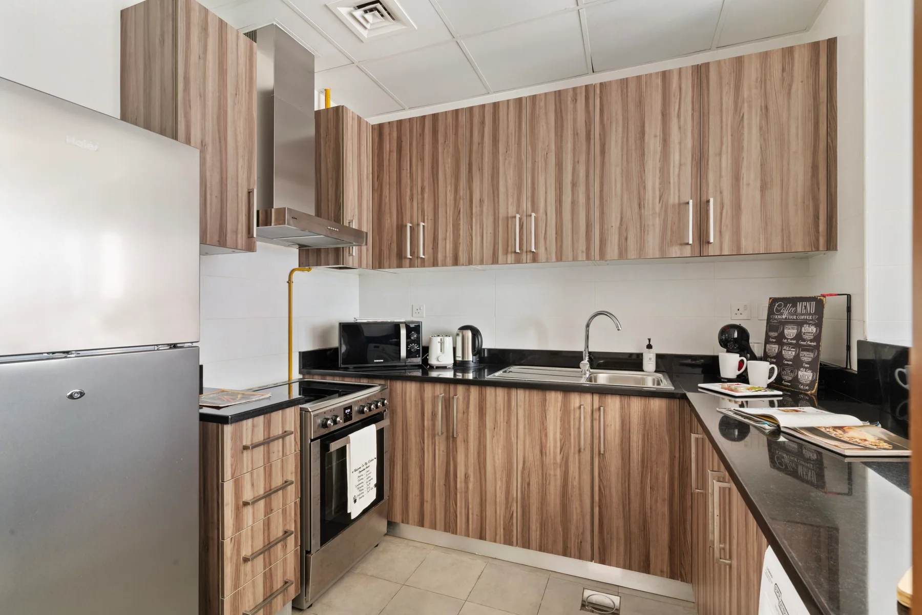 Una cocina compacta con gabinetes color madera, un fregadero y electrodomésticos sobre la encimera.