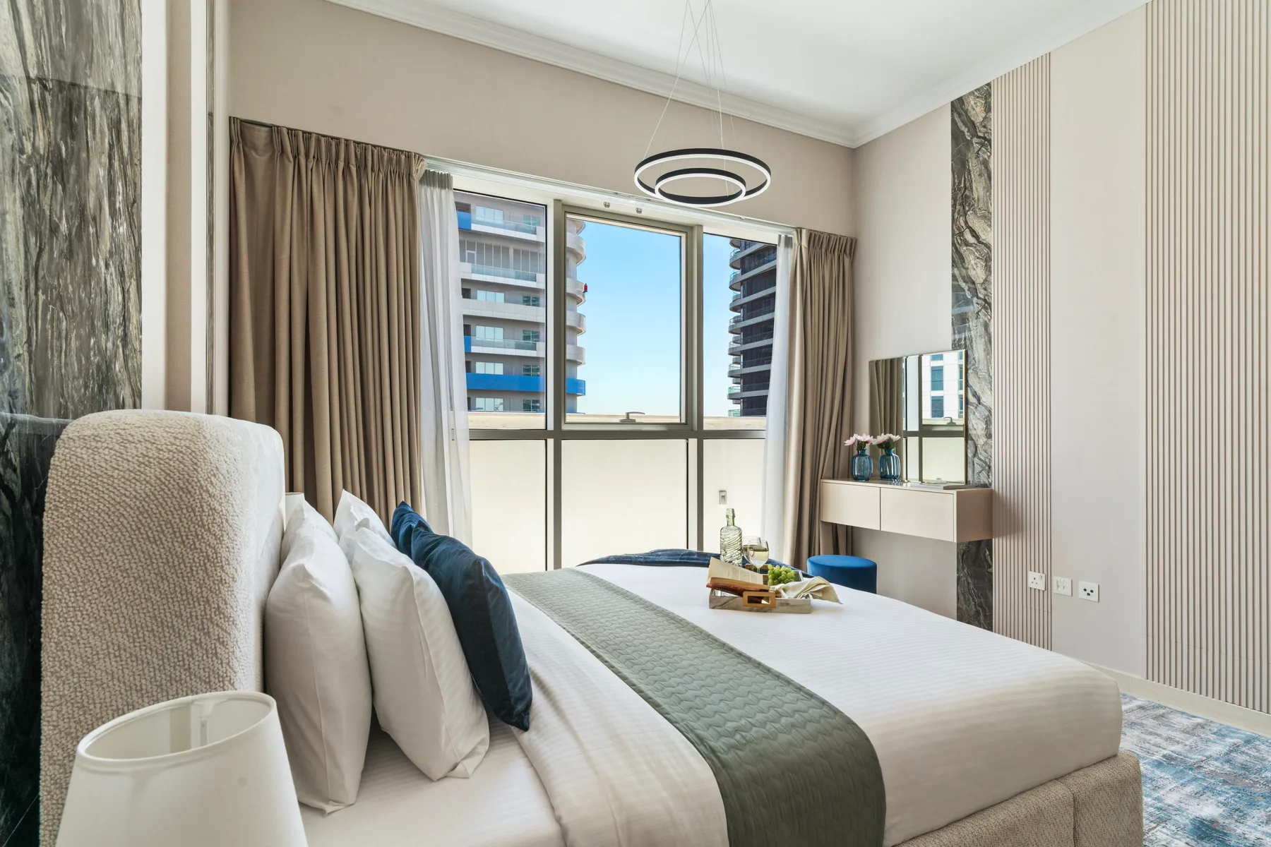 Un dormitorio luminoso con una cama bien hecha junto a una ventana grande.