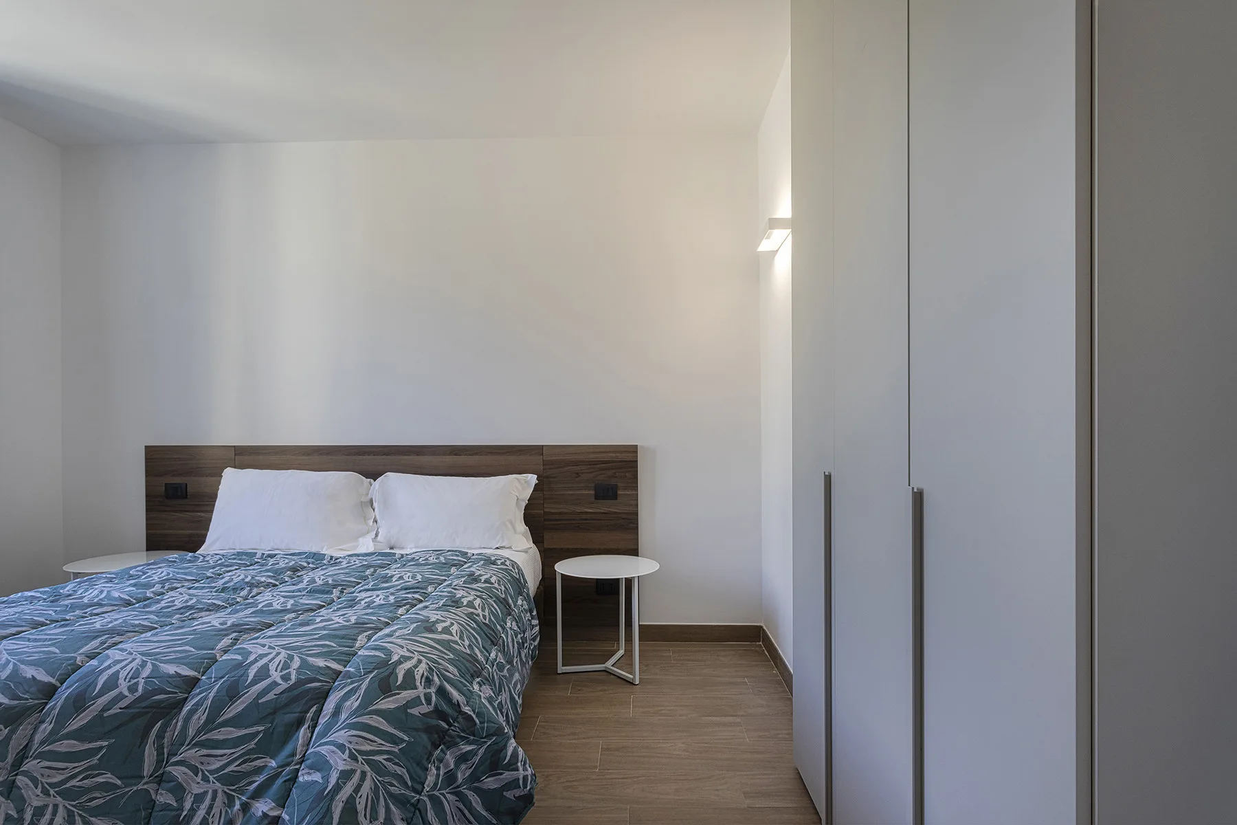 Un dormitorio con una cama, ropa de cama estampada y un armario.