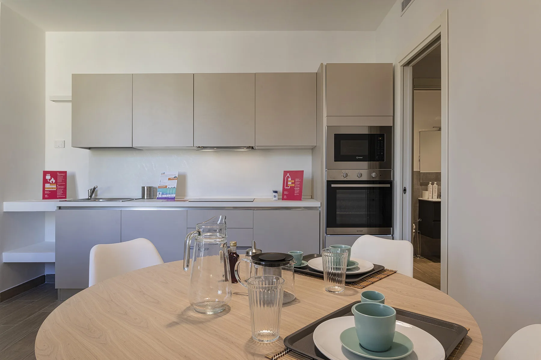 Una cocina moderna con gabinetes claros y una mesa de comedor con vasos y tazas.