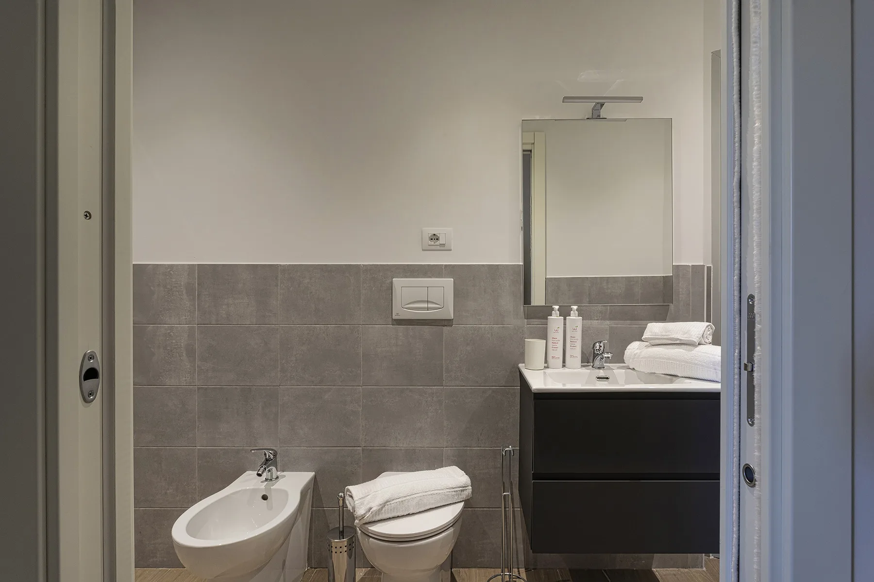 Un baño con lavabo, inodoro y espejo sobre el tocador.